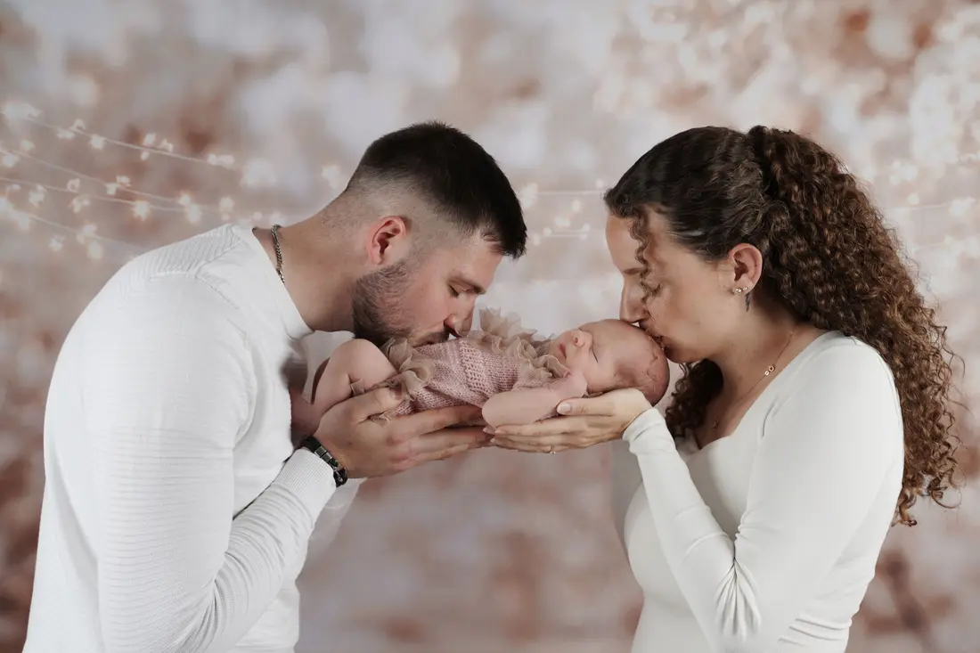 Eltern küssen ihr neugeborenes Baby – Familienfotografie im Studio in Spenge